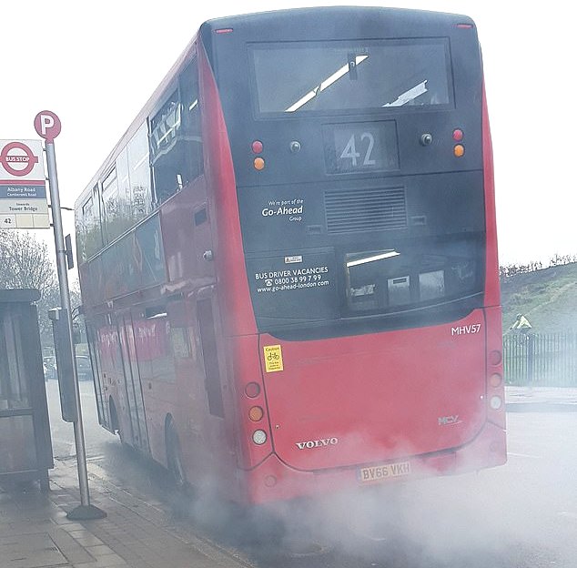 A very dirty diesel powered red bus, in the United Kingdom